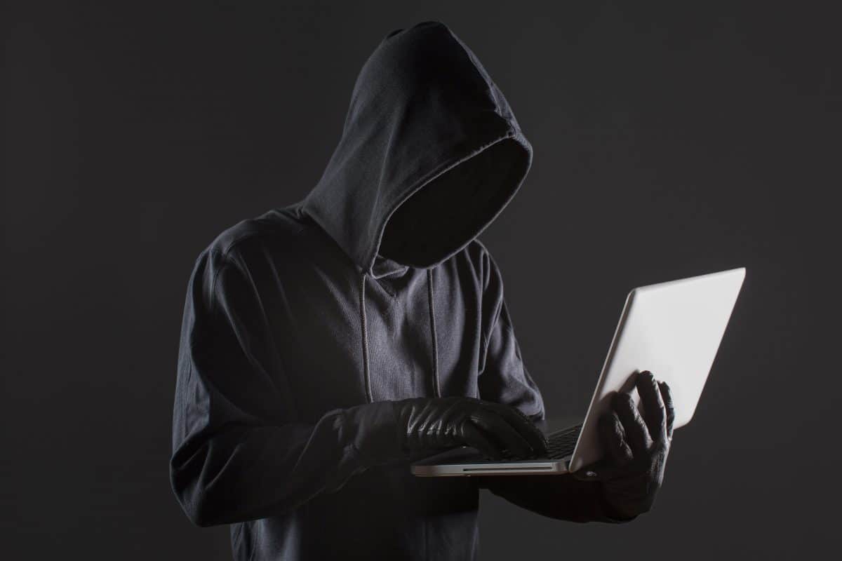 imagen de un hacker anónimo sosteniendo una computadora portátil